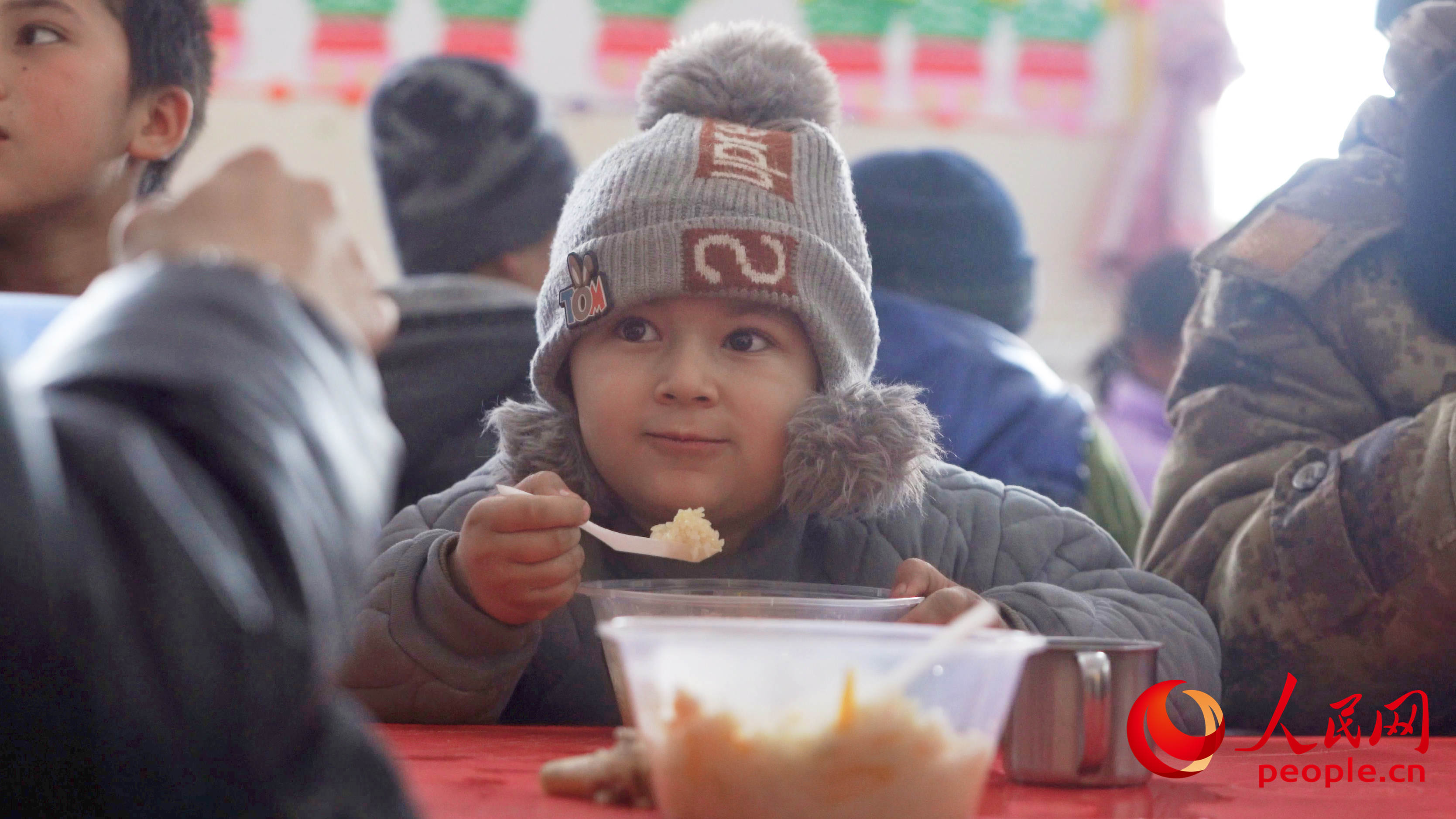 1月24日中午，乌什县亚曼苏乡中心幼儿园安置点，一个娃娃正在吃抓饭。人民网 李欣洋摄